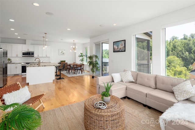 living room featuring a notable chandelier, plenty of natural light, recessed lighting, and light wood-type flooring