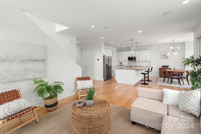 living room featuring an inviting chandelier, recessed lighting, light wood-type flooring, and baseboards