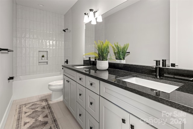 bathroom with a sink, toilet, bathtub / shower combination, and double vanity