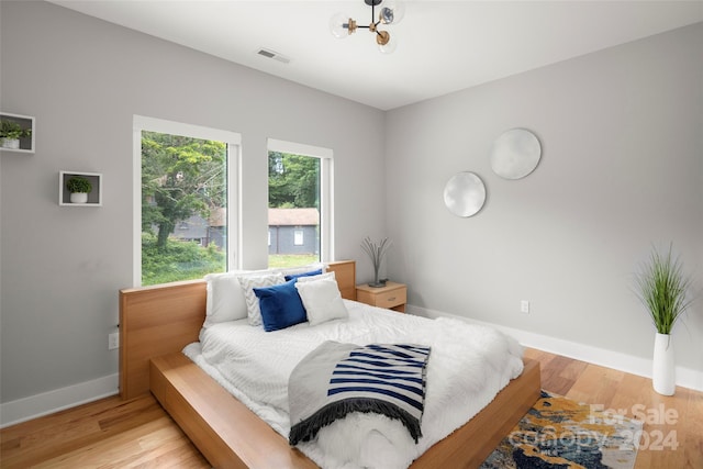 bedroom with visible vents, light wood-type flooring, and baseboards