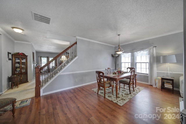 dining room with hardwood / wood-style floors, ornamental molding, and a textured ceiling