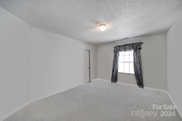 carpeted empty room with a textured ceiling