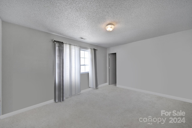 carpeted empty room featuring a textured ceiling