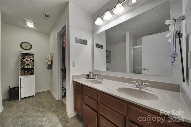 bathroom featuring vanity, a textured ceiling, and a shower with door