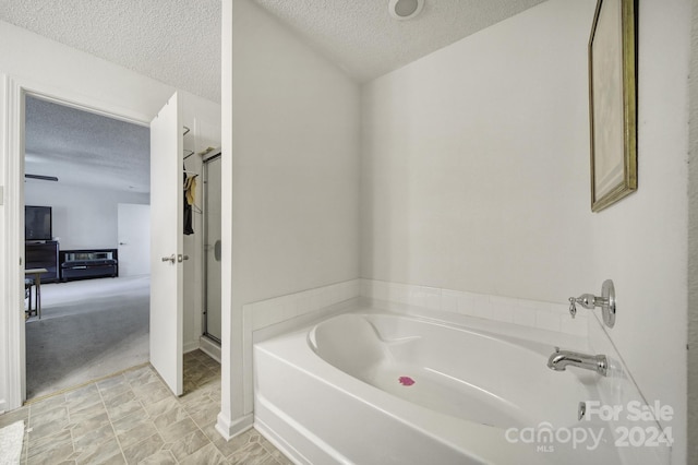 bathroom with a textured ceiling and a bathtub