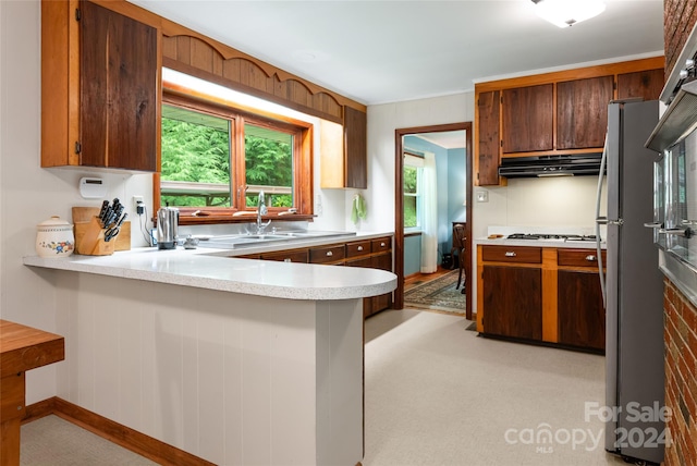 kitchen featuring stainless steel fridge, sink, light colored carpet, and kitchen peninsula