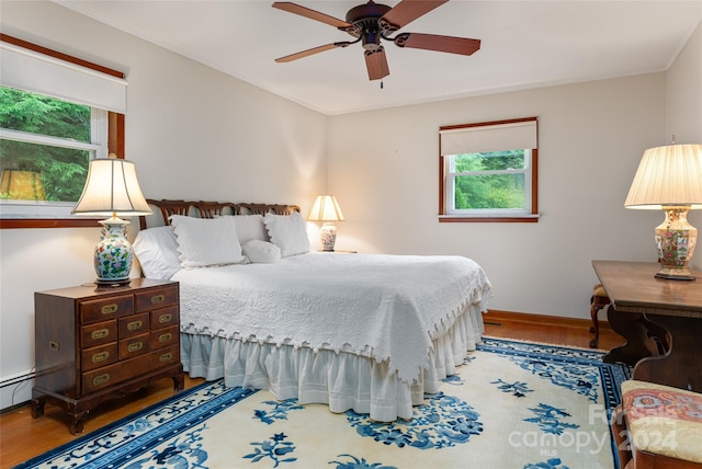 bedroom featuring hardwood / wood-style flooring, crown molding, and ceiling fan