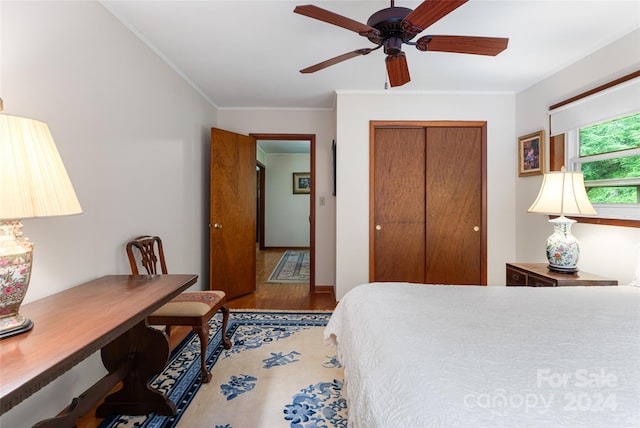 bedroom with a closet, ornamental molding, hardwood / wood-style floors, and ceiling fan