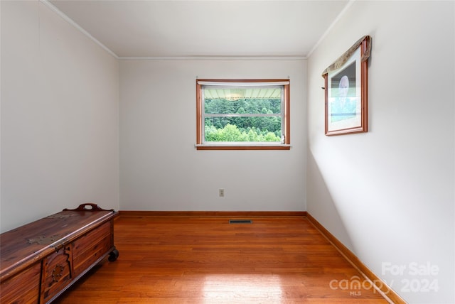 spare room featuring hardwood / wood-style flooring and ornamental molding