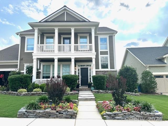 view of front of property with a garage, a balcony, and a front lawn