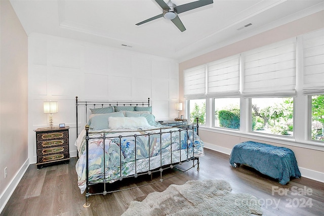 bedroom with a raised ceiling, ceiling fan, and wood-type flooring