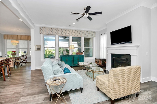 living room featuring ceiling fan, ornamental molding, and wood-type flooring