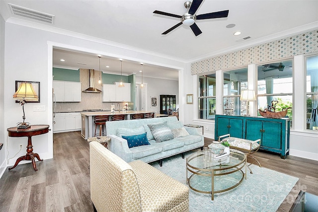 living room with light wood-type flooring, crown molding, and ceiling fan