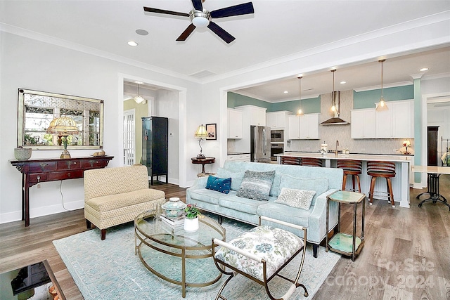 living room featuring sink, crown molding, and light wood-type flooring