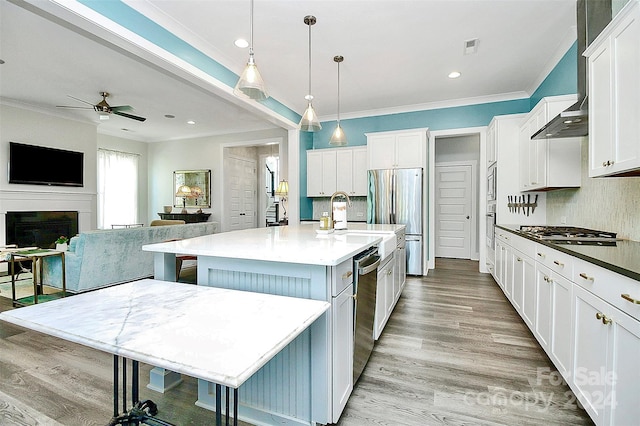 kitchen featuring a center island with sink, hanging light fixtures, and white cabinets