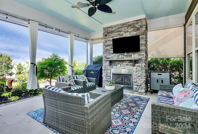 exterior space with ceiling fan, concrete flooring, an outdoor stone fireplace, and a wealth of natural light