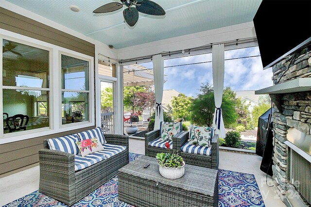 sunroom featuring ceiling fan and an outdoor stone fireplace