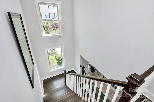 stairs featuring hardwood / wood-style floors, a notable chandelier, and a towering ceiling