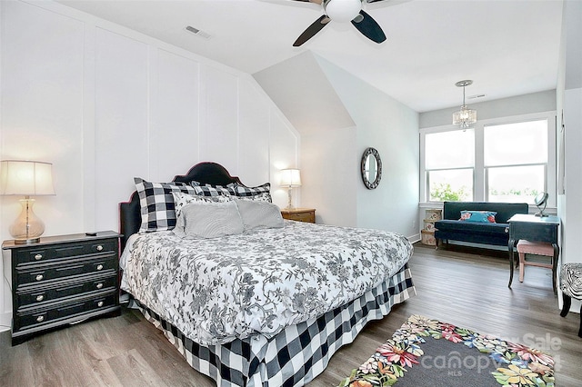 bedroom with ceiling fan with notable chandelier and wood-type flooring