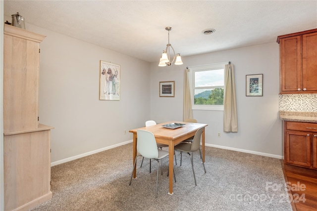 carpeted dining room with a chandelier