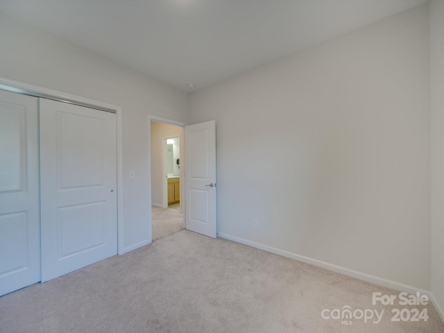 unfurnished bedroom featuring light carpet and a closet