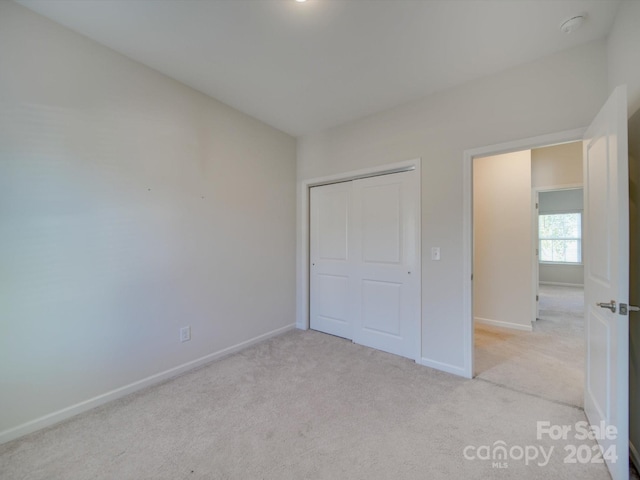 unfurnished bedroom featuring light carpet and a closet