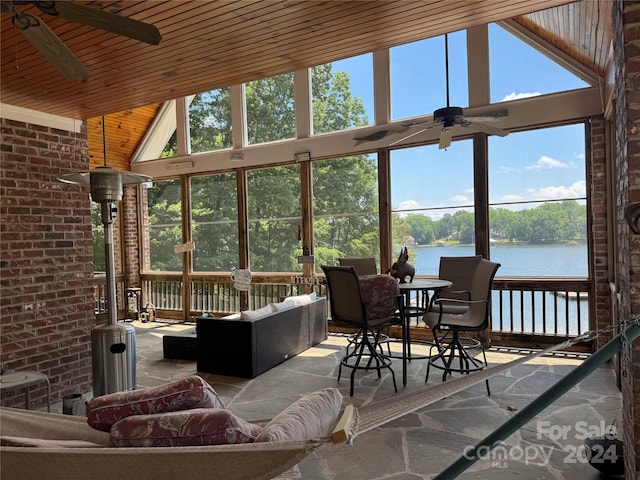 sunroom featuring a water view, vaulted ceiling, ceiling fan, and wood ceiling