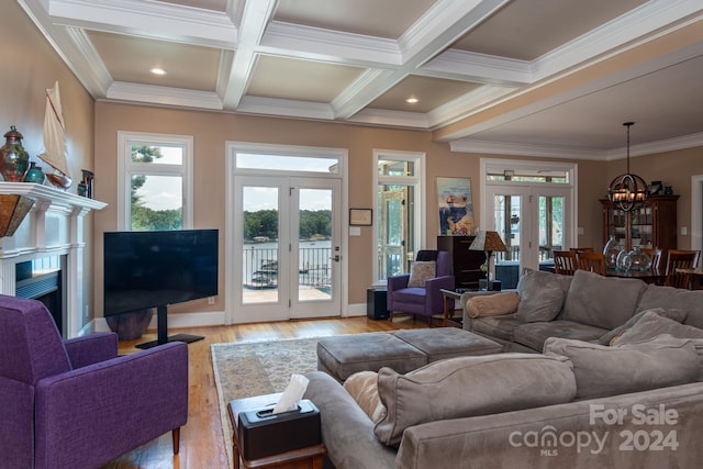 living room with french doors, a wealth of natural light, ornamental molding, beamed ceiling, and a chandelier