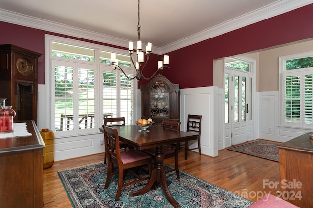 dining space with light hardwood / wood-style flooring, a notable chandelier, a healthy amount of sunlight, and crown molding