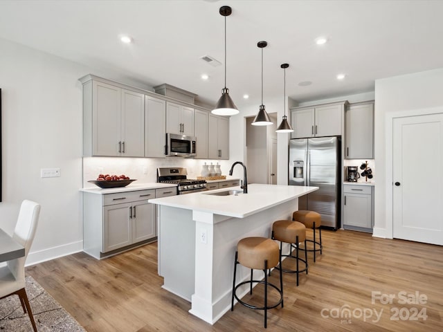 kitchen with a kitchen bar, sink, appliances with stainless steel finishes, and gray cabinets