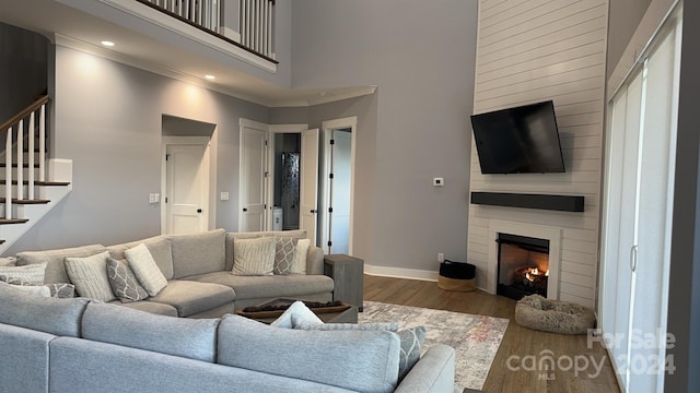 living room featuring ornamental molding, dark hardwood / wood-style flooring, a towering ceiling, and a fireplace