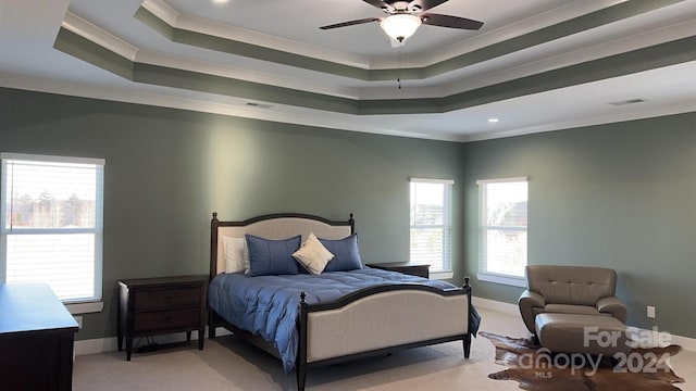 carpeted bedroom with ceiling fan, ornamental molding, and a raised ceiling