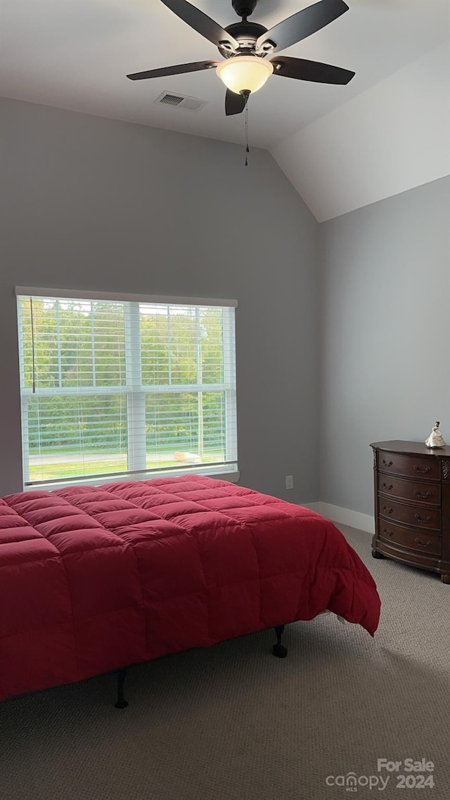 carpeted bedroom featuring ceiling fan, vaulted ceiling, and multiple windows