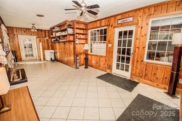 interior space with wooden walls, crown molding, and ceiling fan