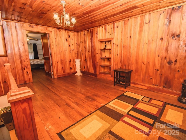 interior space featuring hardwood / wood-style floors, wooden ceiling, wooden walls, and an inviting chandelier