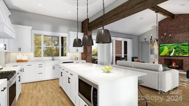 kitchen with gas range, white cabinetry, a kitchen island, and built in microwave