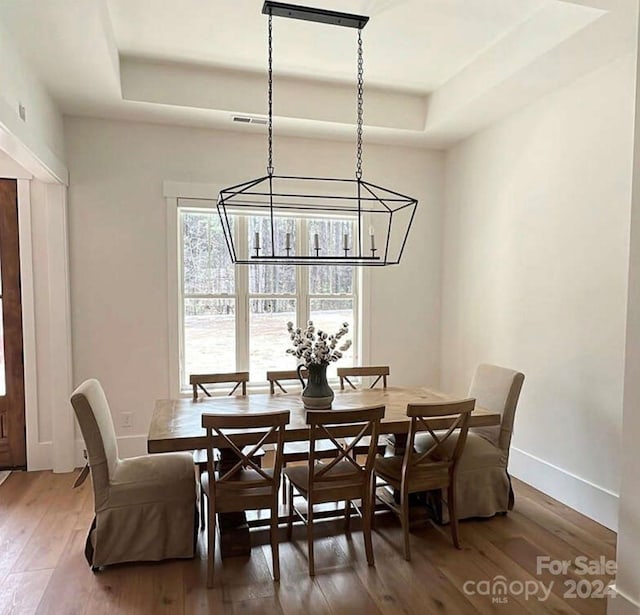 dining space featuring a raised ceiling, dark hardwood / wood-style flooring, and a chandelier