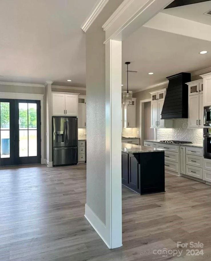 kitchen with white cabinetry, a center island, light hardwood / wood-style flooring, premium range hood, and appliances with stainless steel finishes