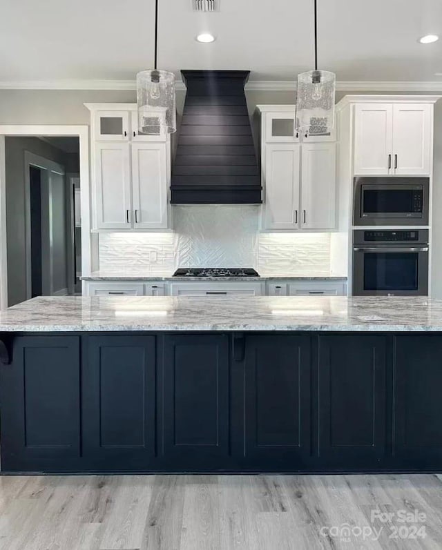 kitchen featuring hanging light fixtures, white cabinets, custom exhaust hood, and appliances with stainless steel finishes