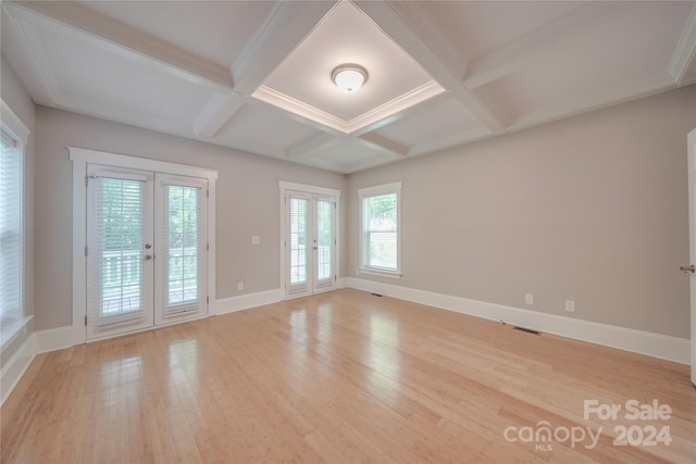 empty room with french doors, coffered ceiling, beam ceiling, and light hardwood / wood-style flooring