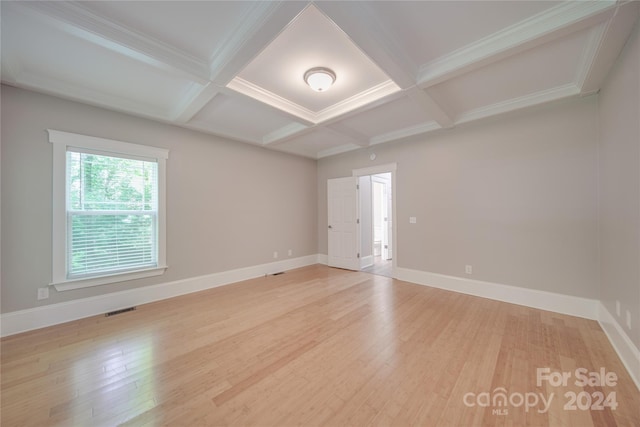 empty room with coffered ceiling, beam ceiling, and light hardwood / wood-style flooring