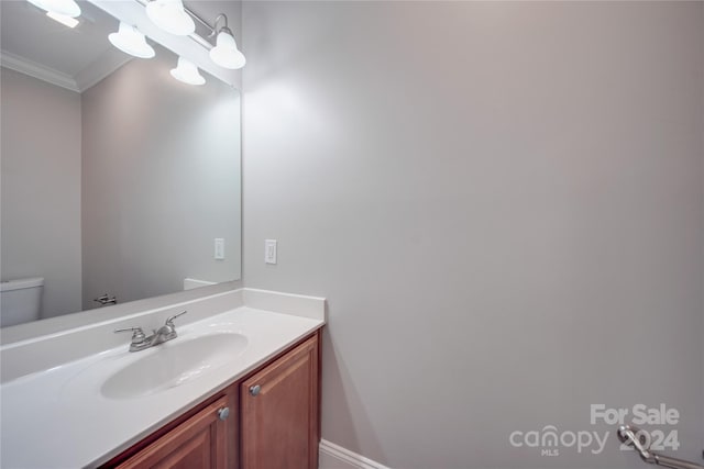 bathroom with ornamental molding, vanity, and toilet