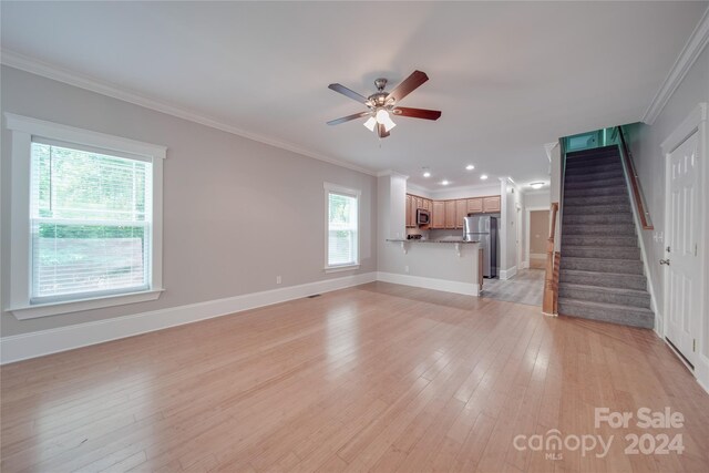 unfurnished living room with crown molding, ceiling fan, and light wood-type flooring