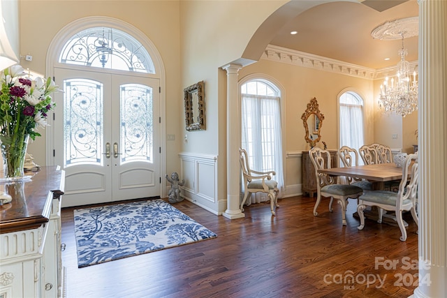 entrance foyer featuring french doors, an inviting chandelier, dark hardwood / wood-style flooring, decorative columns, and crown molding