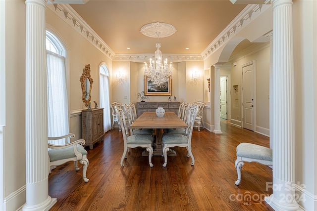 dining area with decorative columns, ornamental molding, wood-type flooring, and an inviting chandelier