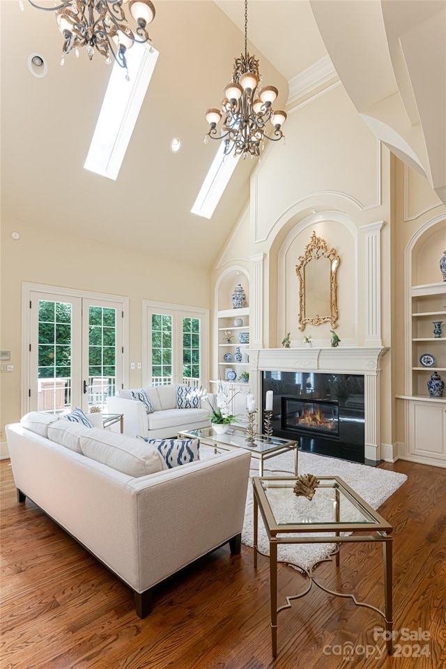 living room with high vaulted ceiling, french doors, an inviting chandelier, hardwood / wood-style flooring, and built in shelves