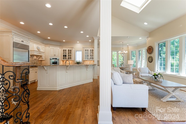 kitchen featuring a large island, dark hardwood / wood-style floors, backsplash, decorative columns, and appliances with stainless steel finishes