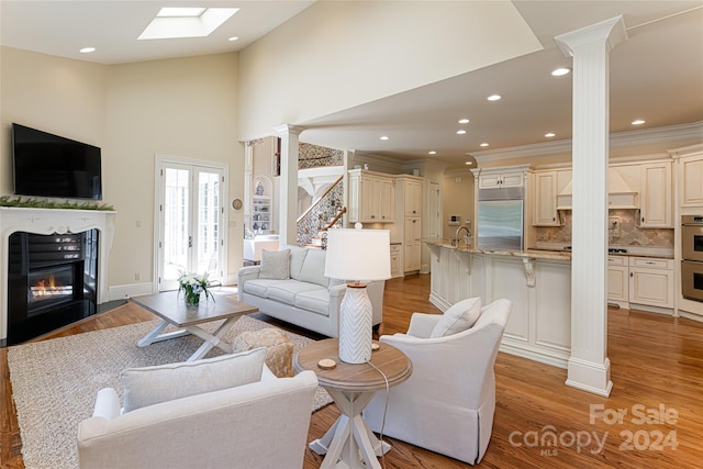 living room with a high ceiling, light hardwood / wood-style flooring, and sink