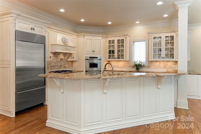 kitchen with tasteful backsplash, light stone counters, a kitchen island with sink, and appliances with stainless steel finishes