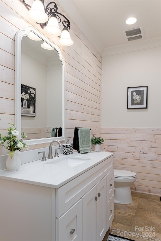 bathroom featuring vanity, toilet, ornamental molding, and wooden walls